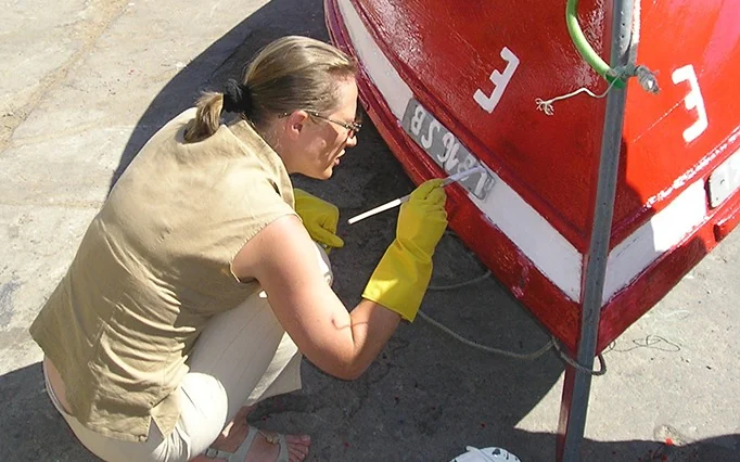 Un atelier de peinture de bateaux : une participante peint un bateau de pêche traditionnel
